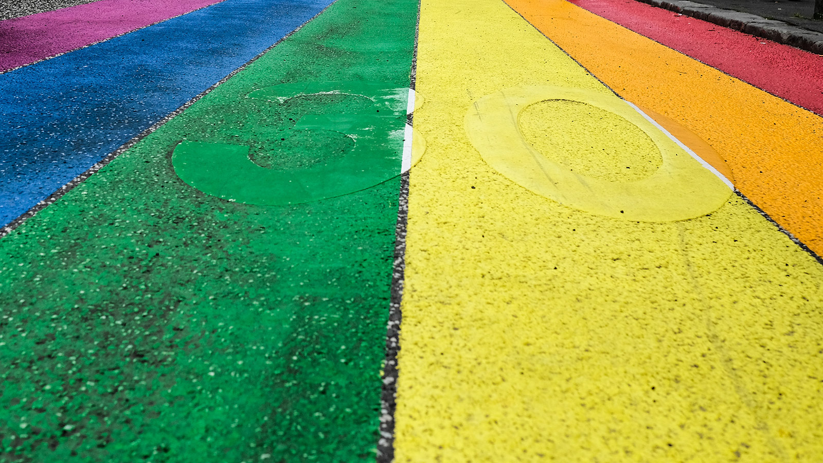 A road covered in paint in the colours of the rainbow