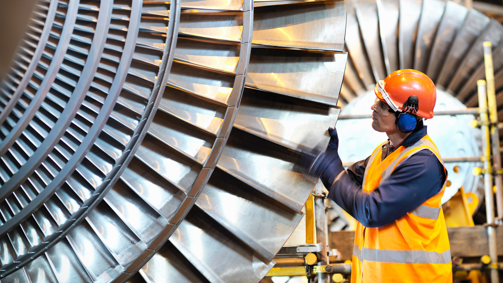 A worker inspects a turbine in a power station