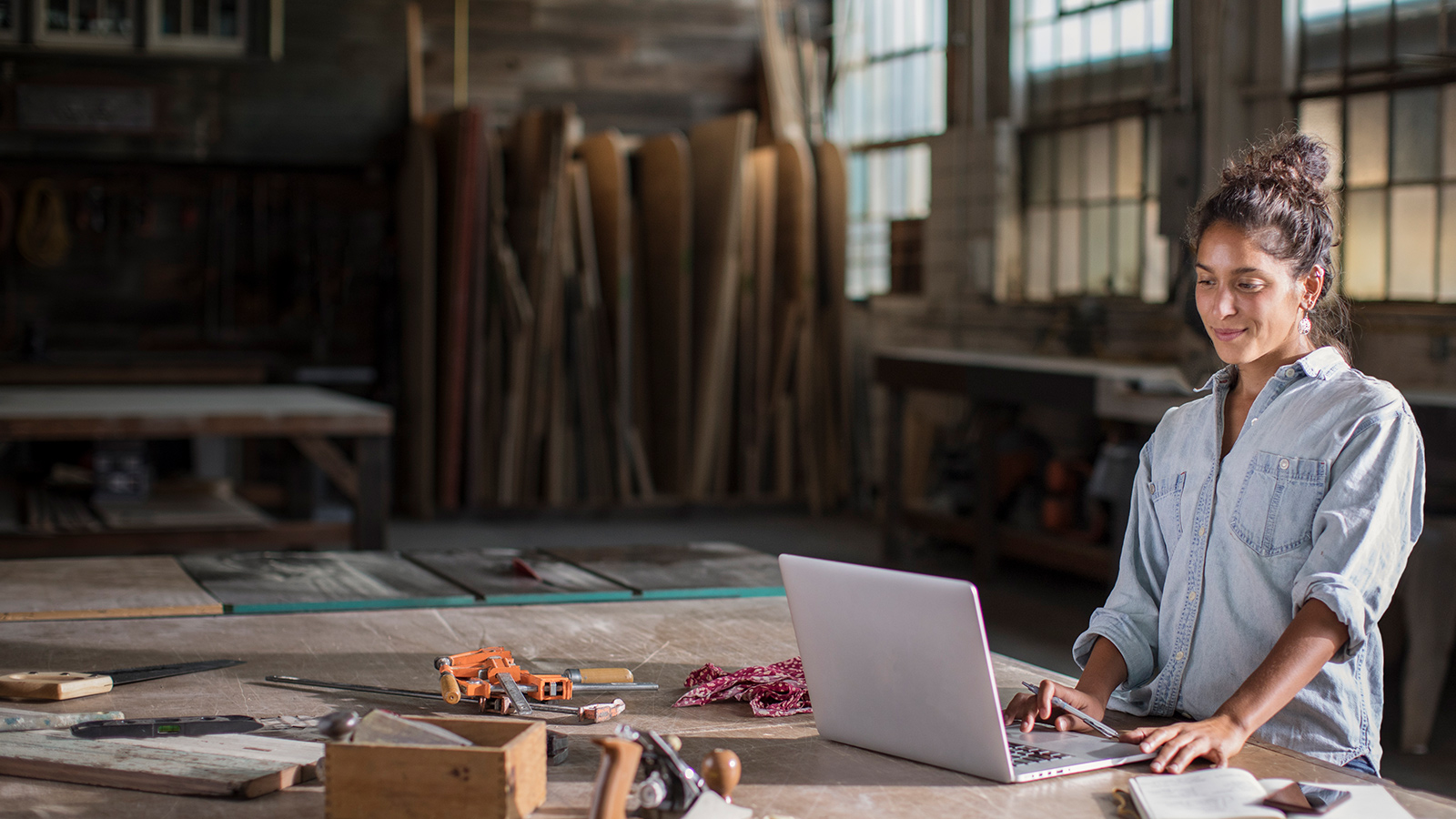 Young Mixed Race Female Entrepreneur Solving a Complicated Business Challenge with Pencil, Laptop, Carpentry Tools, and Confidence 