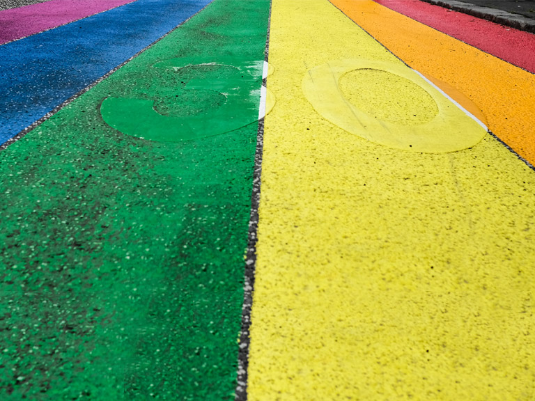 A road covered in paint in the colours of the rainbow