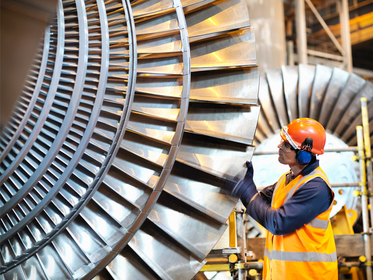 A worker inspects a turbine in a power station