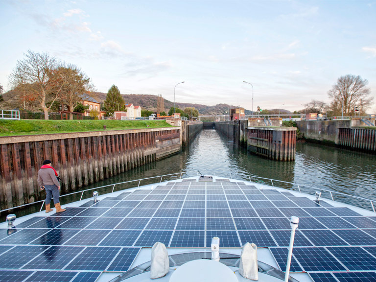 A boat covered with solar panels in a canal