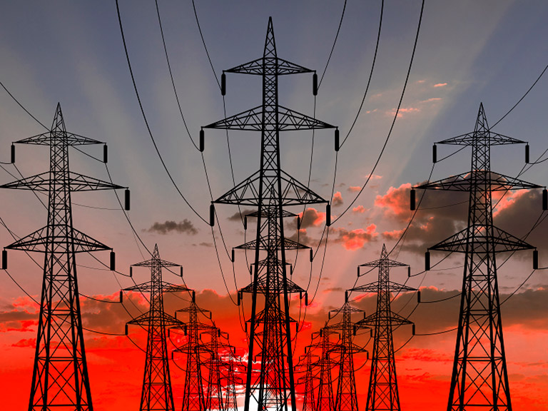 Electricity pylons against a sunset sky