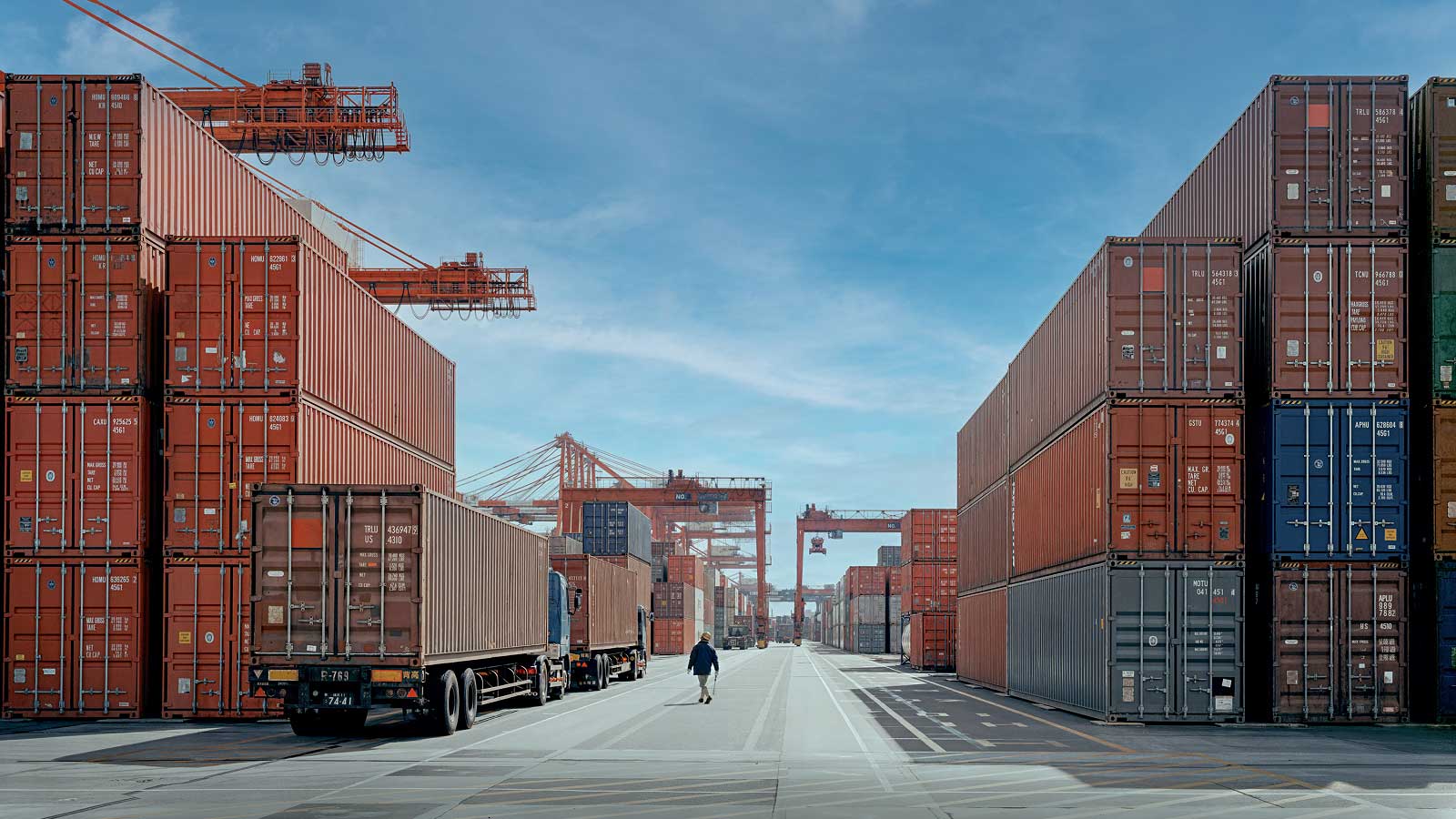 A view of a dock with shipping containers in the background seen through a fishing net in early morning