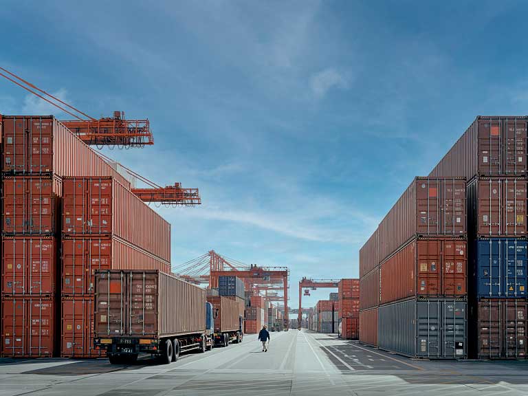 A view of a dock with shipping containers in the background seen through a fishing net in early morning